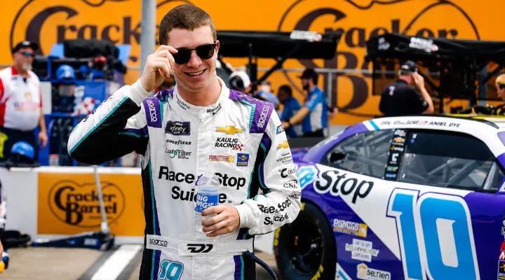 Race to Stop Suicide driver Daniel Dye stands in front of the No. 10 NASCAR race car during race weekend, wearing his racing suit and supporting suicide prevention awareness.